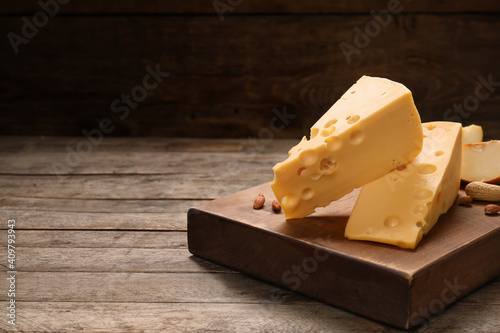 Pieces of tasty cheese and peanuts on wooden background