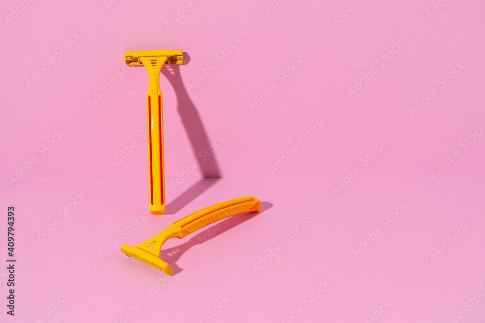 Yellow disposable razors on pink background, studio shot Yellow disposable razors on pink background, studio shot