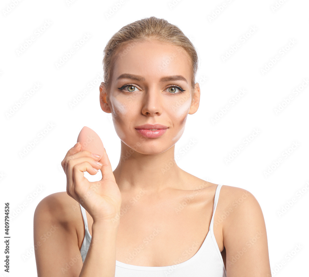 Beautiful young woman applying contouring makeup against white background Beautiful young woman applying contouring makeup against white background