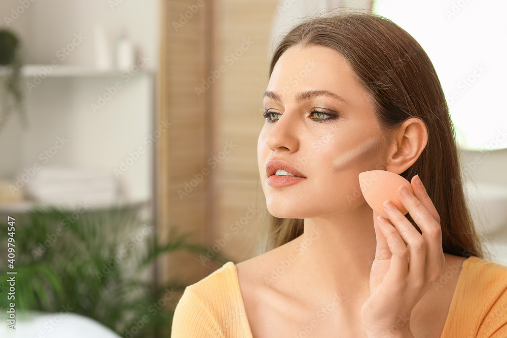 Beautiful young woman applying contouring makeup at home Beautiful young woman applying contouring makeup at home