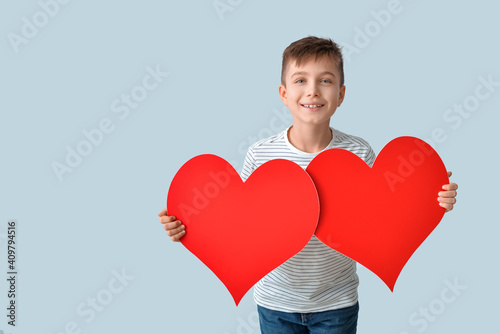 Cute little boy with red hearts on grey background