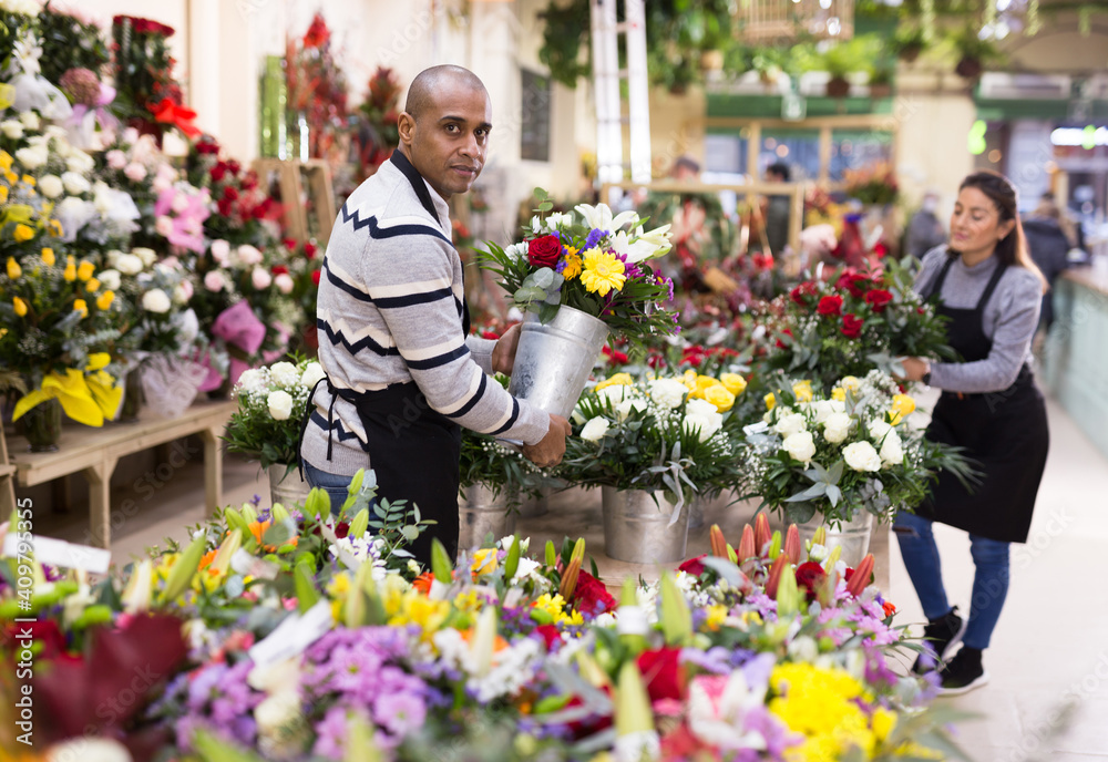 Florist man in apron creates bouquets in flower shop