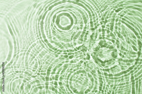 Transparent and clean green water background with sunlight reflection