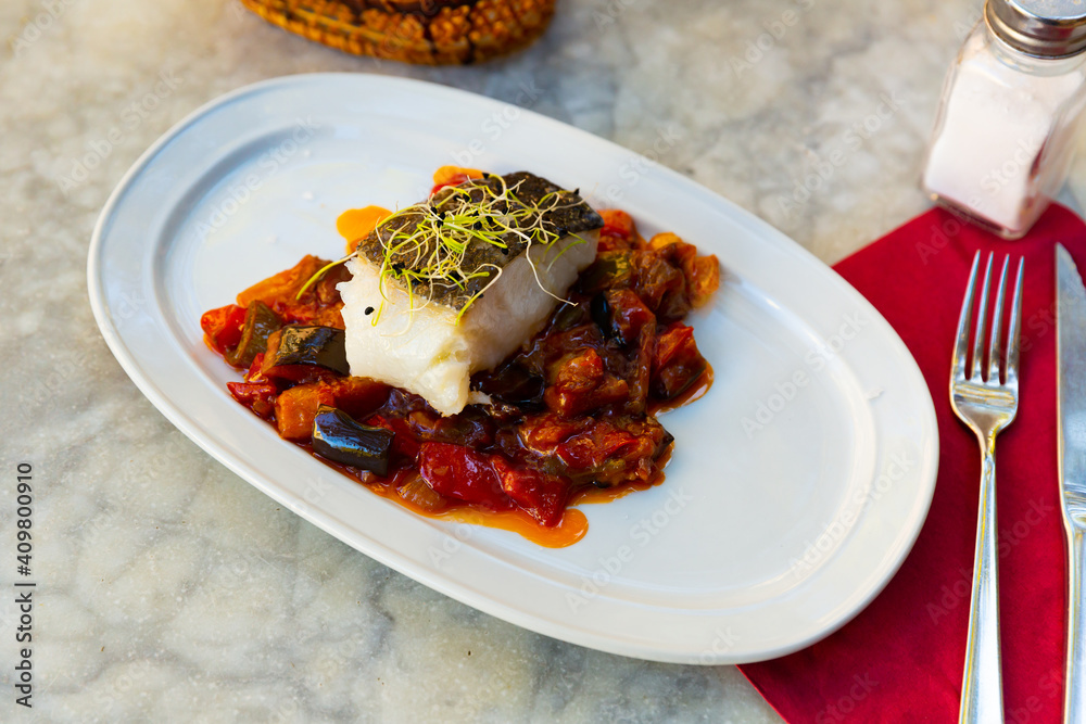 cuisine spanish candied fish with stewed vegetables served on white plate