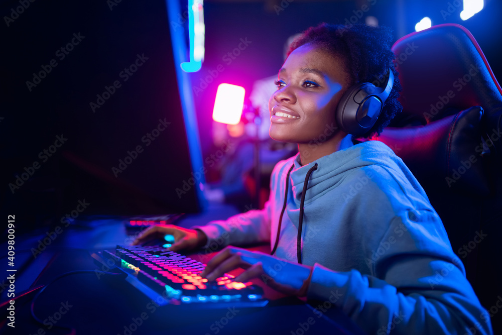 Professional Streamer African young woman cyber gamer studio room with personal computer armchair, keyboard in neon color blur background - obrazy, fototapety, plakaty 