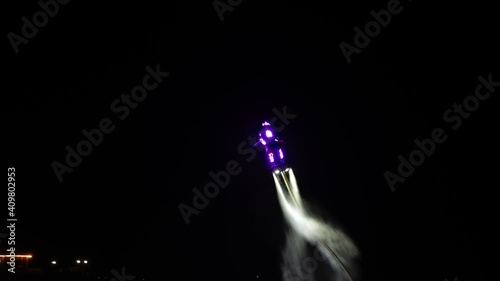 An unrecognizable flyboarder is making tricks at night. High quality 4k footage photo