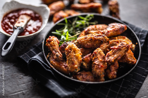 Chicken wings barbeque in a cast iron baking dish with BBQ sauce and rosemary