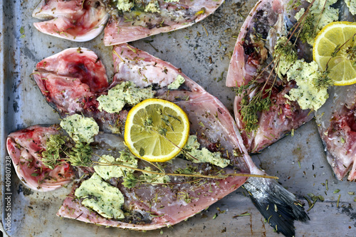 fresco mar dourado peixe com ervas, limão, é sobre um metal cozimento folha, processo de preparação para cozinhar.  photo