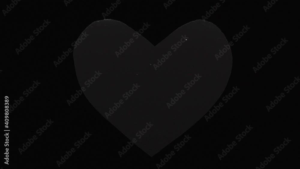 black heart with drops in the rain, on a black background, close-up.