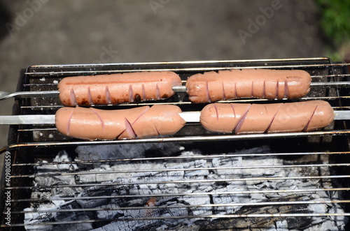 Sausages are cooked on a grill on coals . BBQ, outdoor barbecue . photo