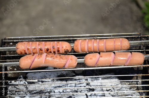 Sausages are cooked on a grill on coals . BBQ, outdoor barbecue . photo