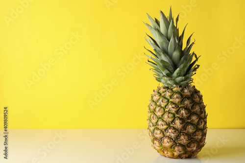 Tasty ripe pineapple against yellow background, space for text