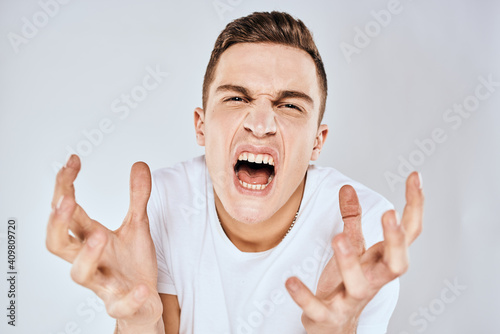 Man in white t-shirt displeased facial expression gesturing with hands studio lifestyle