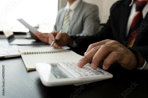 Businessmen use a calculator to calculate company financial statements for their colleagues, view and jointly solve problems within the company. Business finance and accounting concepts