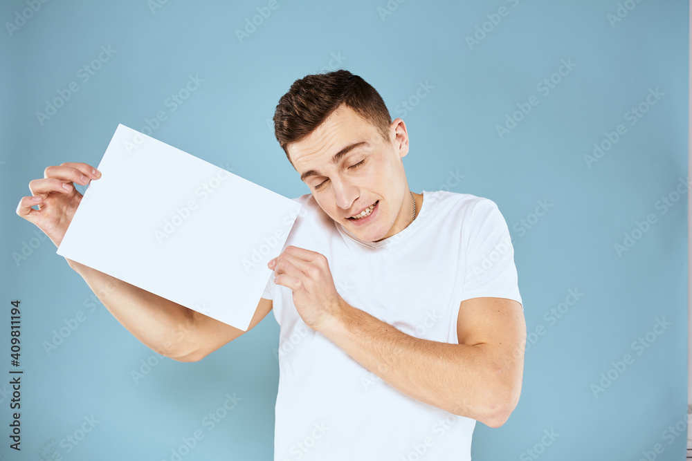 a man in a white t-shirt holds a sheet of paper copy space a man in a white t-shirt holds a sheet of paper copy space