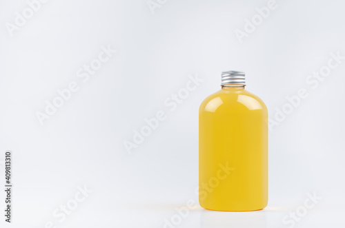 Transparent plastic low thick bottle with orange drink, cooking oil or cosmetic produce with silver cap mockup on white background, template, copy space.