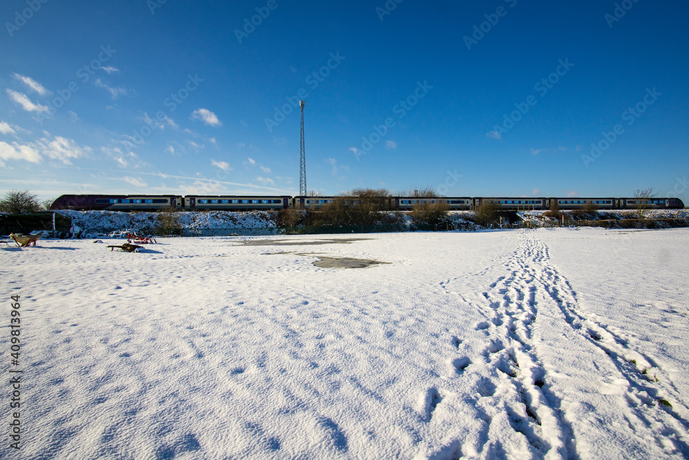 Tracks in a snowy field leading to railway line