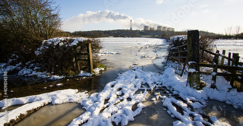 Muddy entrance to flooded field frozen in winter