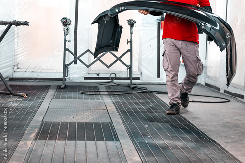 Fotografia A professional mechanic working in a paint chamber during the coating process of a damaged vehicle