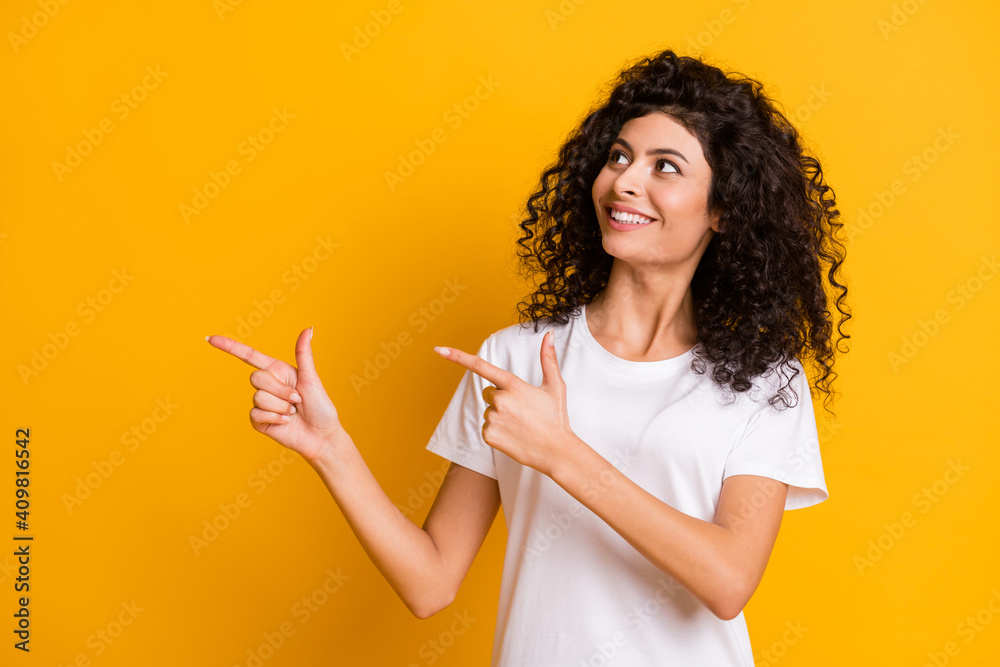 Photo portrait of curly brunette showing looking empty space promoting isolated on bright yellow color background Photo portrait of curly brunette showing looking empty space promoting isolated on bright yellow color background