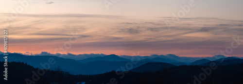 Panorama of the silhouette of mountains and forest on the background of sunset