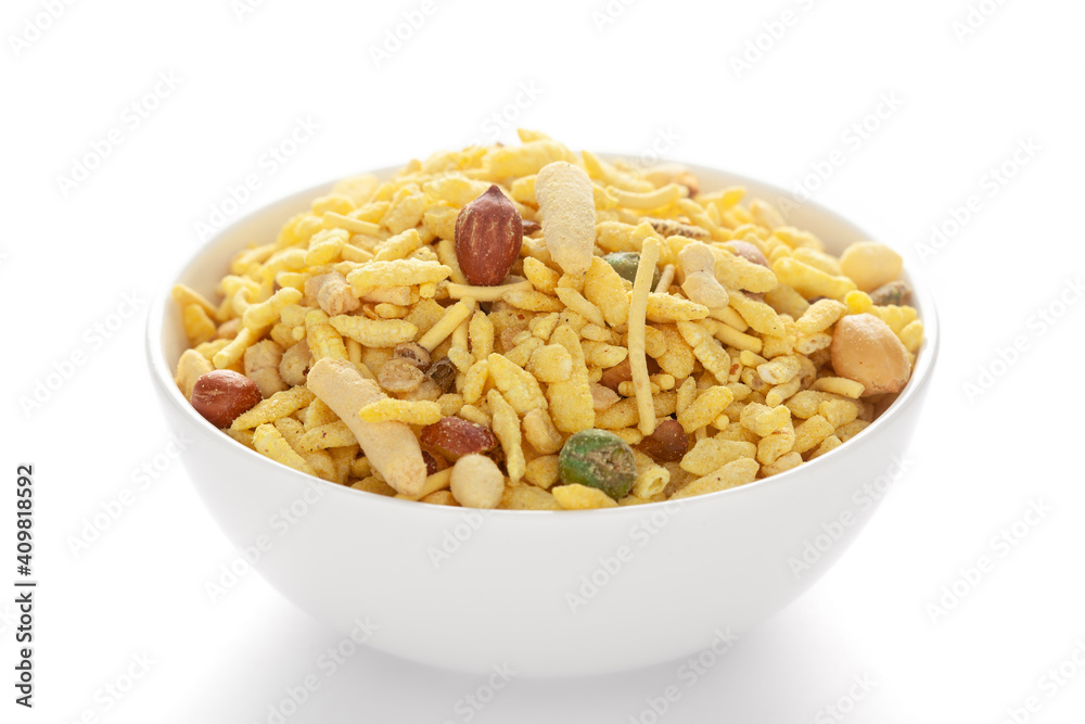 Delicious Khatta Meetha in a white ceramic bowl, made with peanuts, sugar, raisins, and besan sev. Pile of Indian spicy snacks (Namkeen), under backlight, side view, against the white background. Delicious Khatta Meetha in a white ceramic bowl, made with peanuts, sugar, raisins, and besan sev. Pile of Indian spicy snacks (Namkeen), under backlight, side view, against the white background.