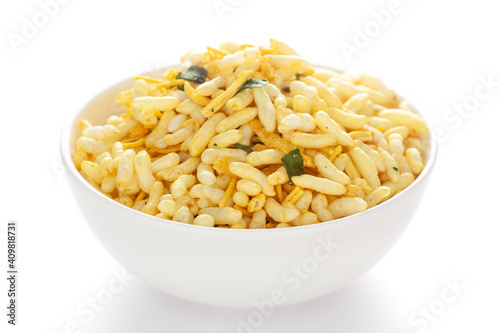 Spicy Chana Jor Garam in a white Ceramic bowl, made with air-fried Bengal Chickpea. Pile of Indian spicy snacks (Namkeen), under backlight, side view, against the white background.