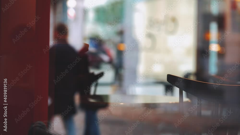 People walk on the street through the window of an empty cafe. Cars are going by. Ordinary city life of the old town. Riga, Latvia