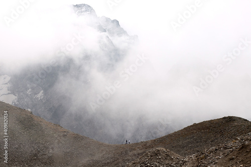 Mountain range in the clouds. Two people are walking along the ridge. Caucasus, Russia