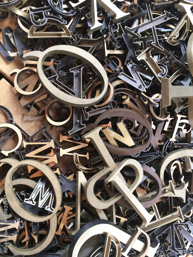 A lot of old metal letters of different sizes are mixed up in an old box. A lot of old metal letters of different sizes are mixed up in an old box.