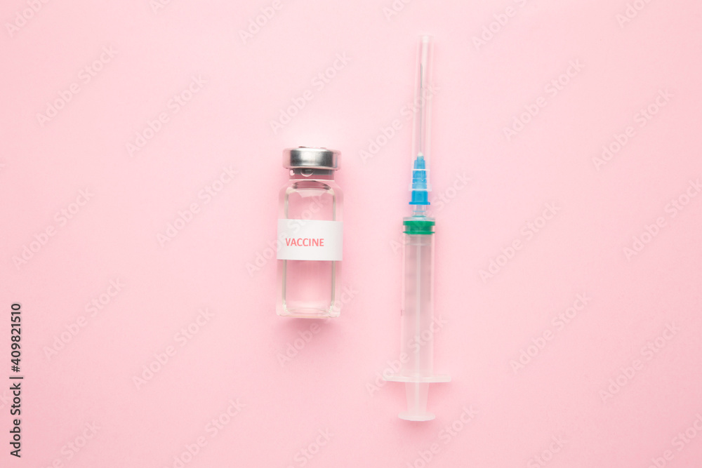 Coronavirus COVID-19 vaccine vials and syringe on pink background with copy space.