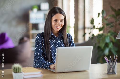 Photo of young beautiful attractive happy smiling positive cheerful businesswoman typing online in laptop at workplace