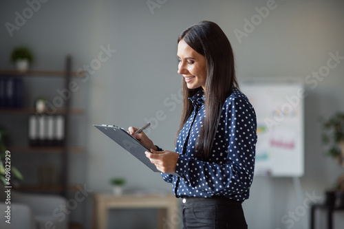 Photos Profile side photo of happy charming woman hold clip board write plan list good