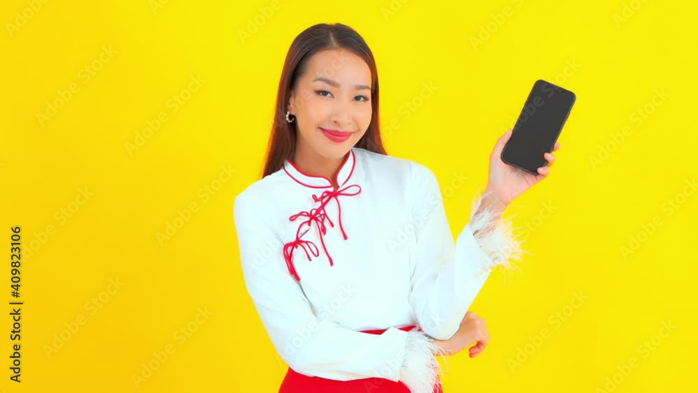 Woman in front of Yellow Backdrop Holds up Smartphone Makes Call Sign Woman in front of Yellow Backdrop Holds up Smartphone Makes Call Sign