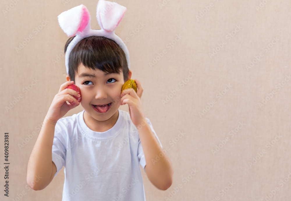 Little cute boy with big eyes, wearing Easter bunny ears, looks up. Little Easter bunny on a light background Little cute boy with big eyes, wearing Easter bunny ears, looks up. Little Easter bunny on a light background