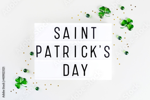 Lightbox with Saint Patricks day text, shamrock symbols made of green hearts and stars confetti on white background. Flat lay Irish holiday party card Spring 17 march lucky clover design photo