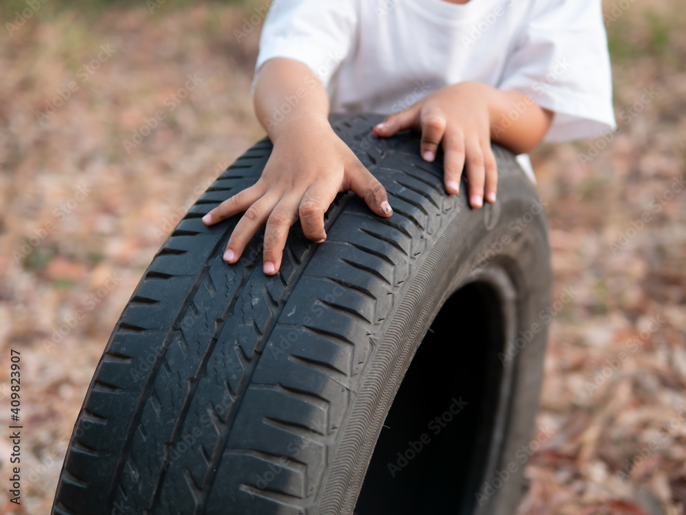 Obraz premium Child dirty hands running auto car tire wheel, playing in relaxing day in rural countryside, preschool learning and freedom fun time concept.