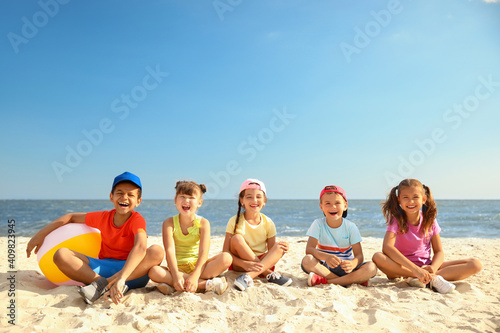 Sticker Group of happy children sitting on sand at sea beach. Summer camp