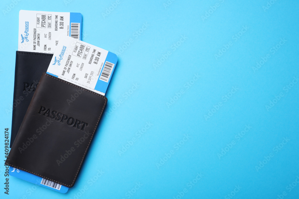 Passports with avia tickets on light blue background, flat lay with space for text. Travel agency concept