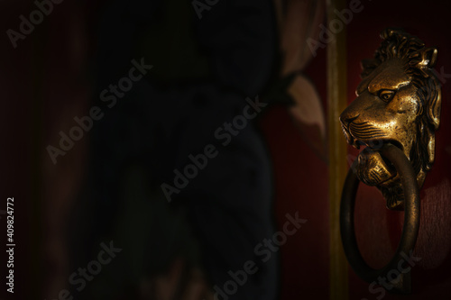Door knocker in the shape of a copper lion's head.Chinese traditional red wooden door.