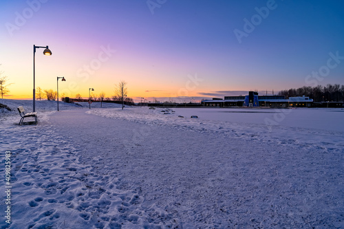 sunrise over path in park covered in snow