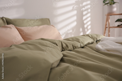 Large bed with soft blanket indoors, closeup