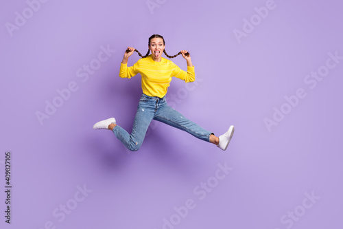 Full body photo of excited young girl jump arms hold play with hair tails tongue out isolated on violet color background © deagreez