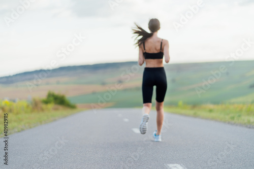 Young fitness woman runner running on city road. Silhouette of a sporty woman running at dawn