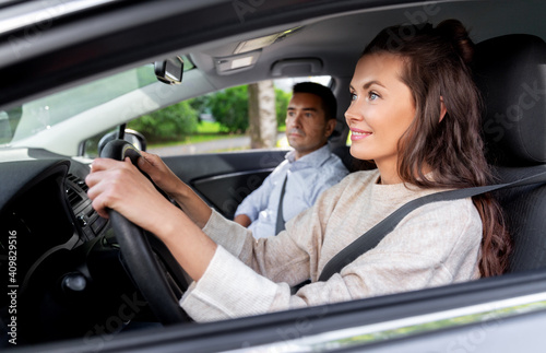 driver courses and people concept - car driving school instructor teaching young woman to drive