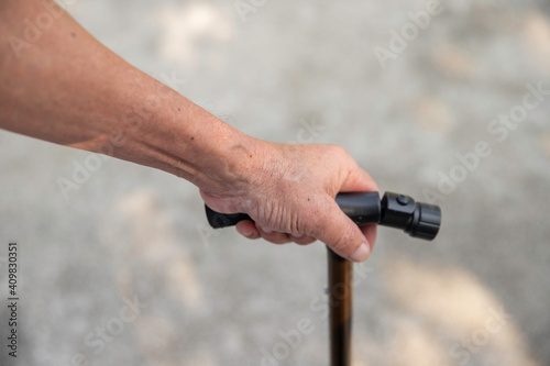Senior man's hand holding walking cane to support himself as he walks, great details.