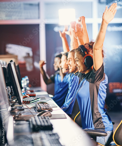 Winning. Young multiracial team of happy professional cyber sport gamers celebrating success, raising hands up while participating in eSports tournament