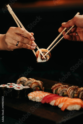 Close-up, couple hands eating sushi food with chopsticks