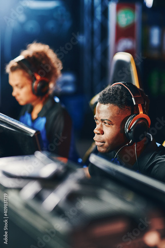 Young focused african guy, cybersport gamer wearing headphones participating in eSport tournament, playing online video games