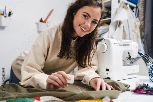 Fotografia, Obraz Portrait of happy seamstress sewing in the workshop